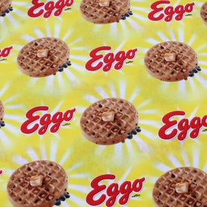May include: A yellow background with a repeating pattern of Eggo waffles and the Eggo logo. The waffles are brown and have a grid pattern. The logo is red and says "Eggo" in a bold font.