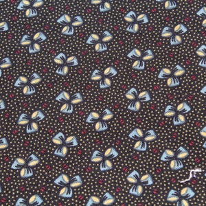 May include: Close-up of a dark fabric with a repeating pattern of stylized blue and yellow flowers. The flowers are set against a background of small, light-colored dots and interspersed with red dots.