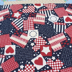 Peut inclure: Un tissu patchwork patriotique avec des motifs rouges, blancs et bleus. Il présente des étoiles, des cœurs, des rayures et des carreaux sur un fond bleu marine. Le texte "AMERICA THE BEAUTIFUL" est également présent.
