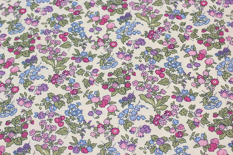 May include: A fabric featuring a dense floral and fruit pattern on a cream background. The design includes small pink, purple, and blue flowers, green leaves, and clusters of red strawberries and dark purple berries scattered across the surface.