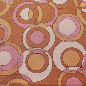 May include: A brown fabric with a repeating pattern of overlapping circles in shades of brown, pink, and white.