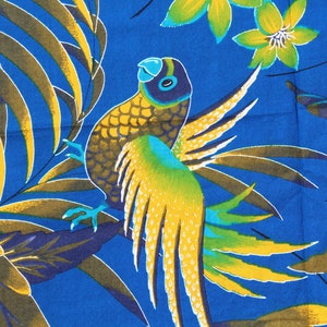 May include: A vibrant blue fabric featuring a repeating pattern of a parrot with yellow and green wings perched among large palm leaves and tropical flowers in shades of yellow, green, and dark brown, creating a dense, colorful botanical design.