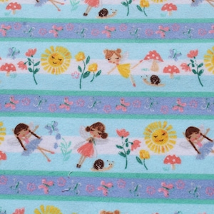 May include: A patterned fabric design with repeating horizontal stripes in light blue and lavender. The stripes are decorated with illustrations of fairies, smiling suns, mushrooms, flowers, butterflies, and snails. The design has a cheerful, fairytale theme.