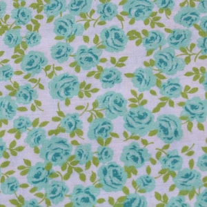 May include: A white fabric with a repeating pattern of light blue roses. The roses are scattered randomly across the fabric.