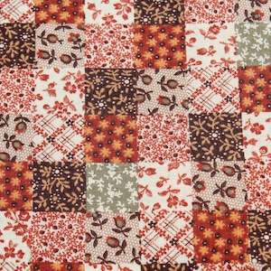 May include: Patchwork fabric with a repeating pattern of squares. Each square features a different floral or geometric design in shades of red, brown, cream, and green. The fabric is likely cotton and suitable for quilting or other crafts.