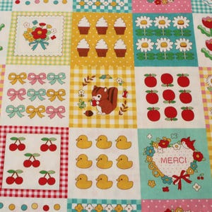 May include: A multi-colored fabric featuring a grid of squares with various patterns including red tulips, white daisies, brown squirrels, yellow rubber ducks, red cherries, red apples, cupcakes, and bows, with one square containing the text MERCI.