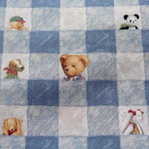 May include: Fabric featuring a blue and white gingham pattern, adorned with cartoon illustrations of a teddy bear, a panda, and dogs. The fabric has a soft texture, with the animal designs centered within each square.