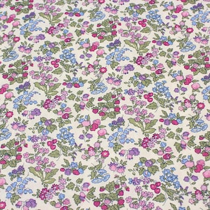 May include: A fabric featuring a dense, repeating floral pattern on a cream-colored background. The design consists of small pink, purple, and blue flowers interspersed with green leaves and stems, creating a continuous botanical print across the surface.