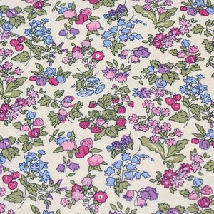 May include: A cream-colored fabric featuring a dense, repeating botanical print. The pattern consists of small pink, purple, and blue flowers, green leaves, and clusters of red strawberries and dark blue berries scattered across the surface.
