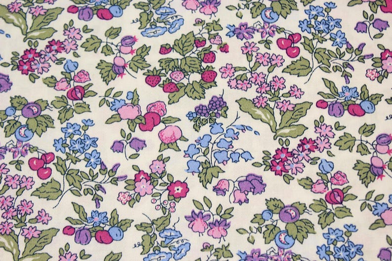 May include: A cream-colored fabric featuring a repeating pattern of small pink strawberries, purple and blue berries, and various small flowers in shades of pink, purple, and blue, all accented with green leaves and stems throughout the design.