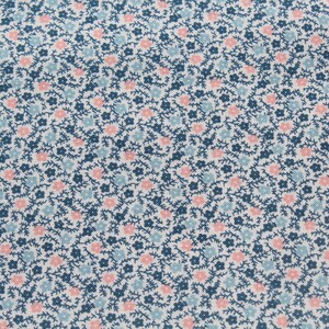 May include: Close-up of a fabric with a repeating floral pattern. The design features small pink and light blue flowers, along with dark blue stems and leaves, set against a white background. The fabric has a textured appearance.