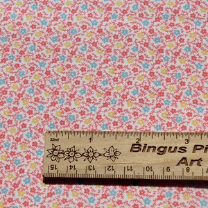 May include: A patterned fabric featuring a repeating floral design in red, yellow, and blue on a white background. A wooden ruler, marked in inches, with the text "Bingus Pingus Art" is placed on the fabric.
