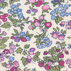 May include: A fabric featuring a repeating botanical print on an off-white background. The pattern consists of small pink, purple, and blue flowers, green leaves, red cherries, and small red strawberries scattered across the entire surface.