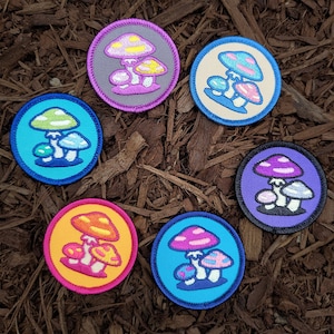May include: Six embroidered iron-on patches featuring different colored mushrooms with white spots. The patches are circular and have a white outline.