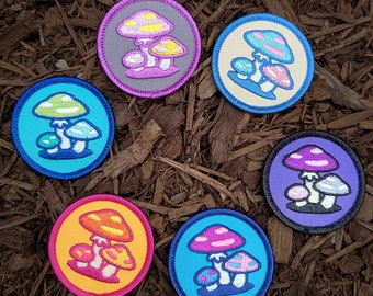 May include: Six embroidered iron-on patches featuring different colored mushrooms with white spots. The patches are circular and have a white outline.