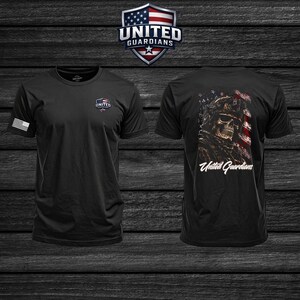 Puede incluir: Una camiseta negra de manga corta con un pequeño logotipo de escudo United Guardians en el pecho izquierdo y una bandera estadounidense blanca en la manga derecha. La parte trasera muestra un cráneo con equipo táctico y una bandera.