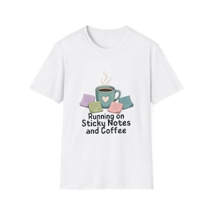Peut inclure: Un t-shirt blanc à manches courtes avec un motif représentant une tasse de café bleu sarcelle ornée d'un cœur, entourée de notes adhésives colorées. De la vapeur s'échappe de la tasse, avec le texte Running on Sticky Notes and Coffee en dessous.