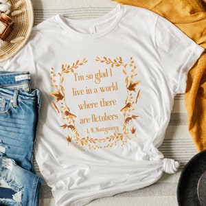 May include: White t-shirt with a gold leaf design and the quote "I'm so glad I live in a world where there are Octobers - L.M. Montgomery"