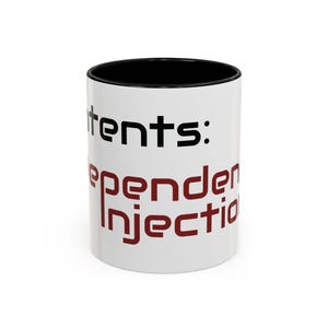 May include: A white ceramic mug with a black interior and rim. The exterior features the black text "tents:" at the top, followed by the dark red text "Dependency Injection" printed in a modern, sans-serif font wrapping around the side.