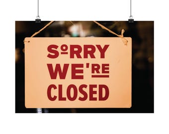 May include: A rectangular light-colored sign hanging by a string with the dark red text "SORRY WE'RE CLOSED" printed in a bold, sans-serif font. The sign features a small "o" superscript after the "S" and an underline beneath the "RE".