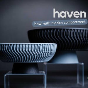 Peut inclure: Deux bols avec un motif ondulé texturé sur l'extérieur et une base solide. Le texte 'haven' et 'bowl with hidden compartment' apparaissent au-dessus des bols. Le plus petit bol est gris clair et le plus grand est gris foncé.