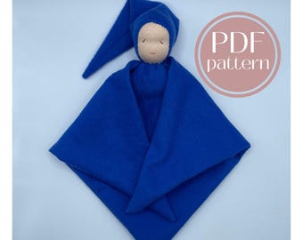 May include: A blue fabric doll with a pointed hat and a simple embroidered face. The doll is wrapped in a blue blanket and is a handmade item.  PDF pattern.