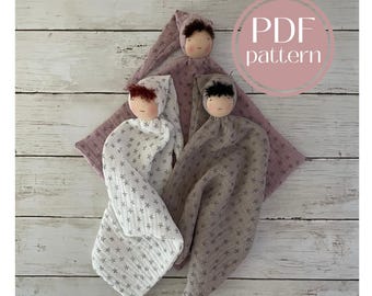 May include: PDF pattern for three fabric baby dolls with star print fabric. The dolls are pink, white, and brown. The dolls have embroidered faces and are lying on a white wooden surface.