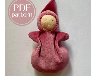 Può includere: Una bambola di feltro rosa con un cappello a punta e un viso ricamato semplice. La bambola è un giocattolo fatto a mano ed è perfetta per i bambini.