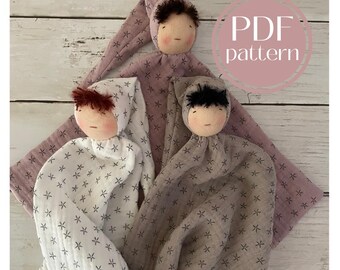 May include: Three handmade cloth dolls with embroidered faces and star patterned fabric. The dolls are wrapped in a blanket and have a PDF pattern label.