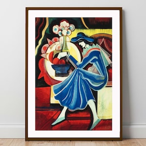 Puede incluir: Una impresión artística enmarcada que presenta una representación estilizada de una mujer con un vestido y sombrero azules, sentada cerca de una mesa con frutas y flores. La obra utiliza colores llamativos y formas geométricas, con una firma en la esquina inferior derecha.