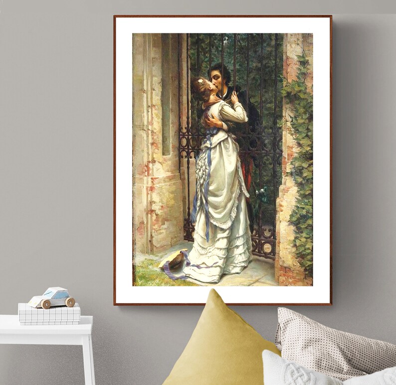 May include: A framed print of a romantic scene. A man and woman embrace and kiss in front of a wrought iron gate. The woman wears a white dress with blue accents. The artwork has a vintage aesthetic.