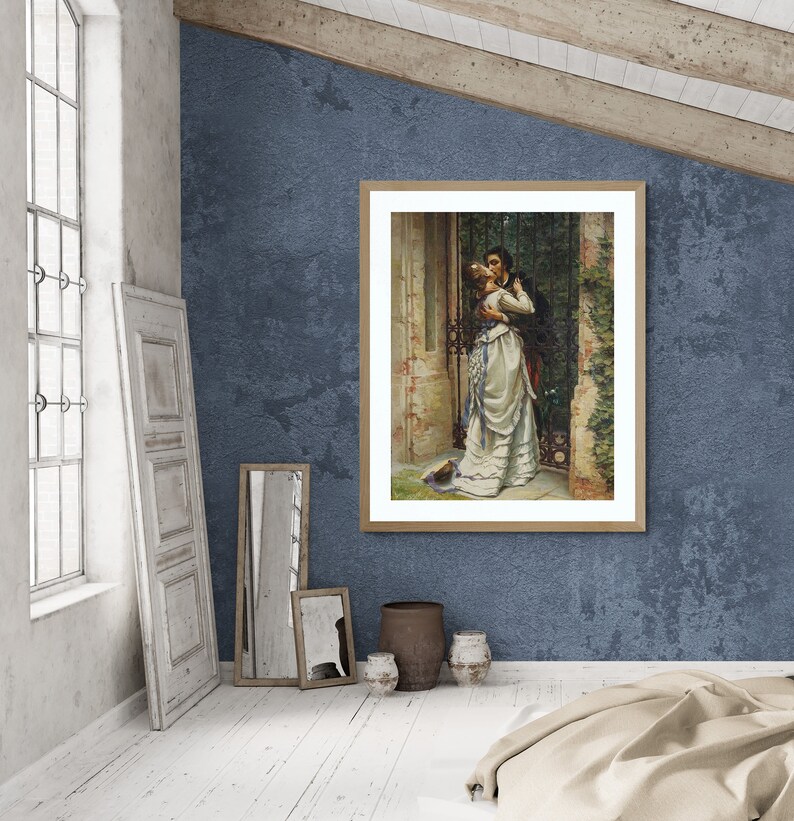 May include: A framed print of a romantic scene. The artwork depicts a couple embracing near a gate. The woman wears a white dress with blue accents, and the man is in a dark suit. The frame is light brown, and the background is a textured blue wall.