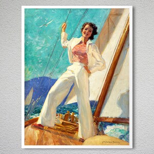 Op de afbeelding: Een vrouw in een wit matrozenpak en een rood gestreept shirt staat op het dek van een zeilboot. Ze houdt een touw vast en kijkt uit over de zee. De lucht is blauw en in de verte zijn witte wolken te zien.