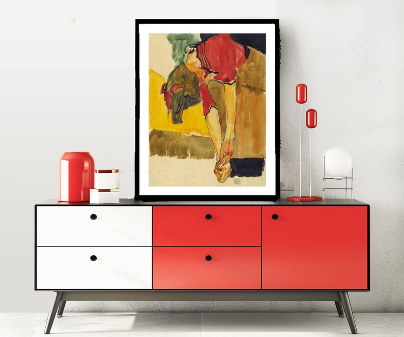 Puede incluir: Una pintura al agua enmarcada de una mujer con un vestido rojo, tumbada sobre un fondo amarillo y marr&oacute;n.