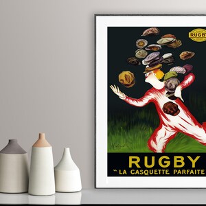 Puede incluir: Un cartel vintage que anuncia gorras "Rugby". El cartel presenta una ilustraci&oacute;n de dibujos animados de una persona haciendo malabares con gorras mientras corre. El texto "Rugby" est&aacute; en letras grandes amarillas con el lema "La Casquette Parfaite" en letras m&aacute;s peque&ntilde;as debajo.
