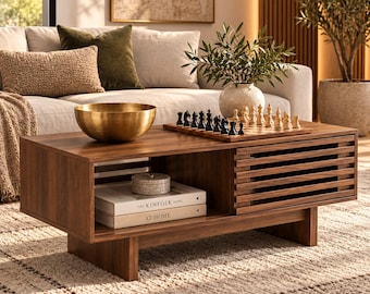 May include: A rectangular wooden coffee table with a slatted sliding door, an open storage shelf, and a low-profile base. The table surface holds a large brass bowl, a wooden chessboard with pieces, and a potted plant in a ceramic vase.