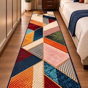 Puede incluir: Una alfombra de pasillo rectangular larga con un patrón geométrico de triángulos y trapecios en varias texturas y colores, incluyendo azul profundo, naranja brillante, rosa suave, crema, rojo oscuro y verde bosque, con borde azul oscuro.
