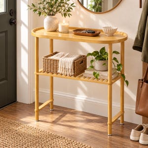 May include: A light-toned bamboo console table with an oval top and a lower shelf. The top holds a speckled vase, a candle, a wooden tray with keys, and a small bowl. The lower shelf features a woven basket with a fringed cloth and a potted plant.