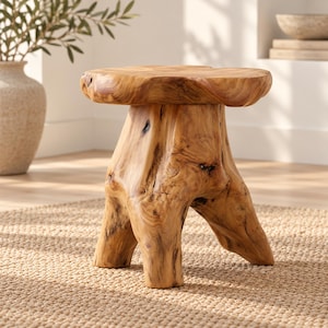 May include: A light brown wooden stool crafted from a single piece of tree trunk, featuring a smooth, circular top and three thick, sturdy legs with visible natural wood grain, knots, and organic textures throughout the entire structure.