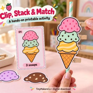May include: A Clip, Stack & Match hands-on printable activity featuring a card with an ice cream cone illustration, a paper ice cream cone attached to a striped straw, wooden clips, and loose paper scoops in purple and brown.