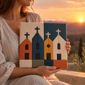May include: A square fabric wall art piece featuring a Kinusaiga pattern of four stylized church buildings in shades of cream, orange, dark blue, olive green, and yellow, each topped with a cross and featuring rectangular doors and windows.
