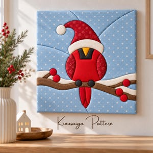 May include: A square fabric wall art piece featuring a Kinusaiga pattern of a red cardinal bird wearing a Santa hat, perched on a brown branch with red berries against a light blue background with white polka dots representing falling snow.