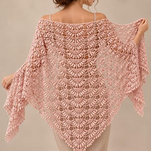 May include: A light pink triangular crochet shawl featuring an intricate fan-shaped pattern with textured bobble stitches throughout. The delicate, openwork design creates a scalloped edge along the bottom, showcasing fine yarn craftsmanship.