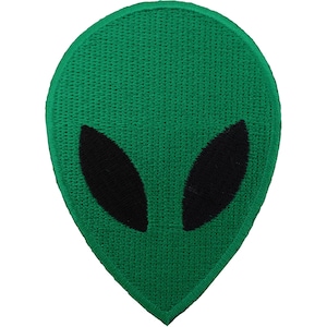 Könnte beinhalten: Ein gestickter Aufnäher in Form eines Alien-Kopfes. Der Aufnäher hat einen leuchtend grünen Hintergrund mit einer strukturierten Stichführung und zwei große, längliche, einfarbig schwarze ovale Formen, die die Augen darstellen.