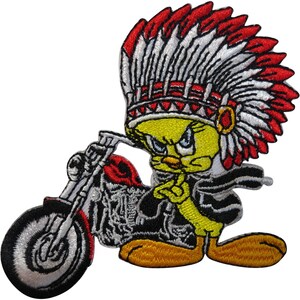 May include: An embroidered patch featuring a yellow cartoon bird wearing a large red and white feathered headdress. The bird is positioned next to a black and silver motorcycle with red accents, appearing to lean against the bike's frame.