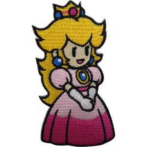 May include: An embroidered patch featuring a cartoon character with long yellow hair, a gold crown with blue and pink accents, blue earrings, and a pink dress with a darker pink skirt, white sleeves, and a central blue brooch on a light pink bodice.
