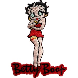 May include: An embroidered patch featuring the cartoon character Betty Boop with black hair, wearing a red dress and gold hoop earrings. The character is positioned above a red banner with the black embroidered text Betty Boop in cursive script.