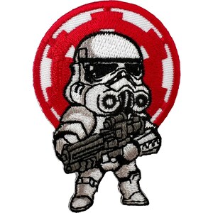 May include: A circular embroidered patch featuring a stylized white stormtrooper character holding a black blaster rifle. The character is centered against a vibrant red and white circular emblem background with a distinct geometric border design.