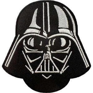 May include: A black and white embroidered patch featuring the iconic helmet design of a fictional character. The patch displays detailed white stitching on a solid black background, outlining the helmet's visor, face mask, and ventilation grill.