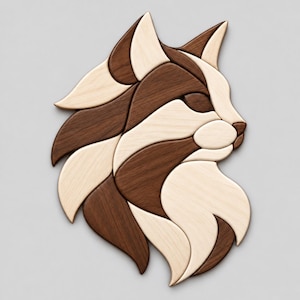 Può includere: Un oggetto da parete realizzato con pezzi di legno chiaro e scuro incastrati tra loro, che formano il profilo di una testa di gatto. Il design presenta segmenti curvi e lisci con venature del legno visibili, alternando toni crema e marrone.